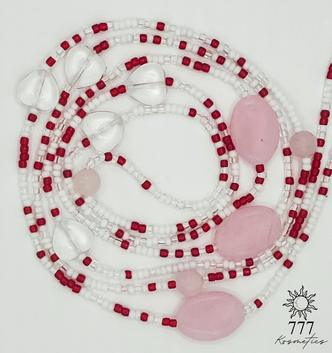 Waist beads that have red, white, and clear seed beads. Along with pink oval beads, genuine rose quartz gemstones, and clear heart beads. 
